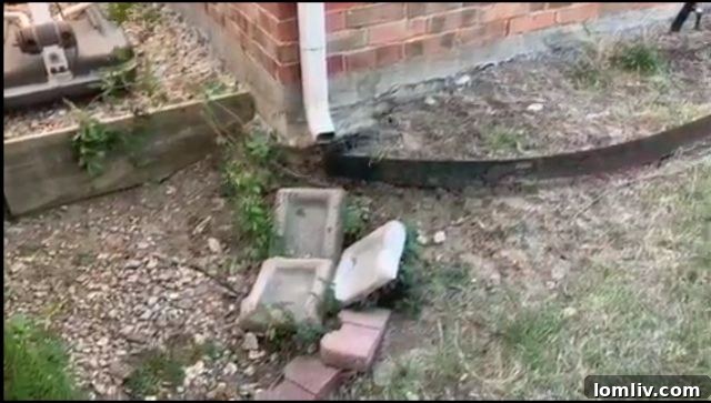 A short downspout ending too close to a house foundation, indicating a potential for water damage and erosion.