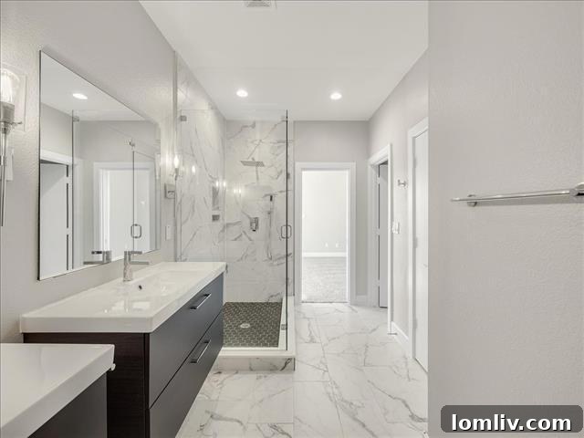 Spa-like master bathroom featuring double sink vanity, elegant tiling, and modern fixtures.