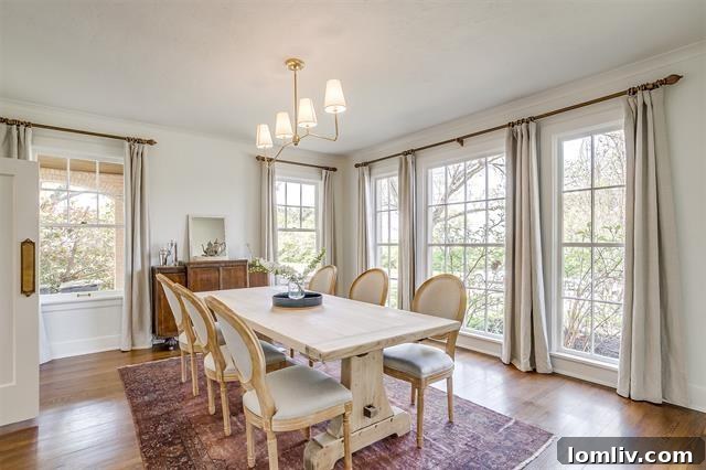 Bright and refined dining room post-renovation, featuring neutral tones, a minimalist chandelier, and long drapes, preserving the historic charm of 2200 Winton Terrace E.