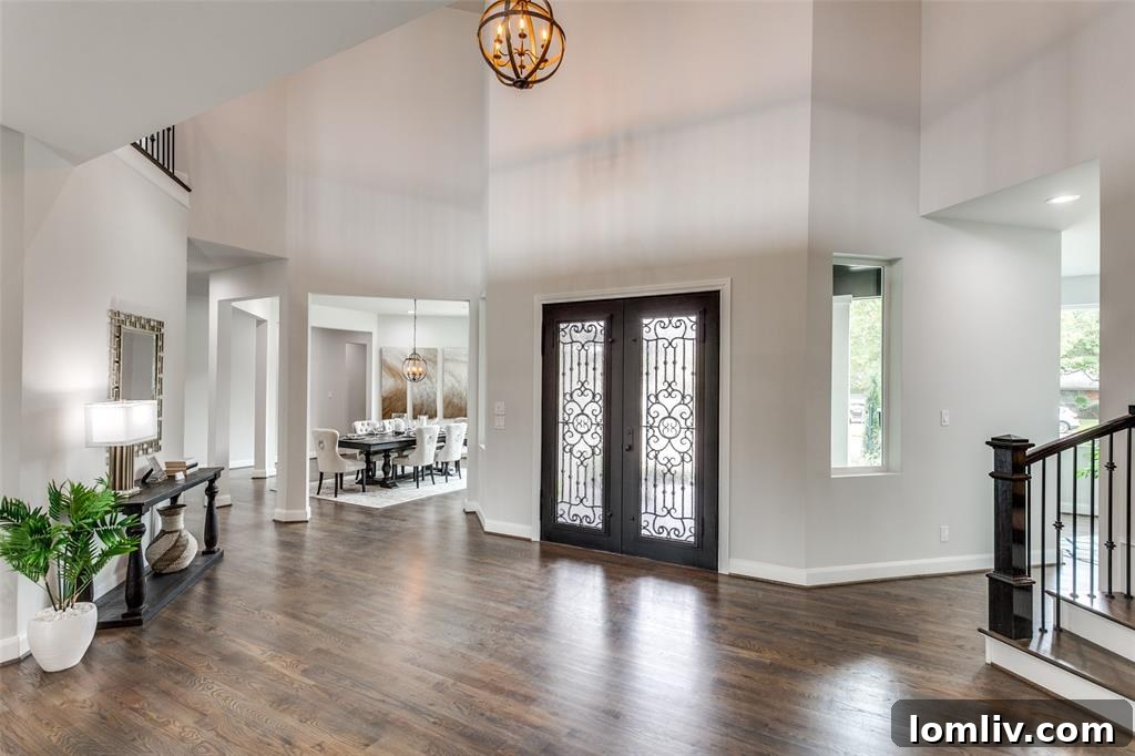 Inviting entryway and grand foyer of the Preston Hollow home, showcasing dark hardwood floors and ample natural light