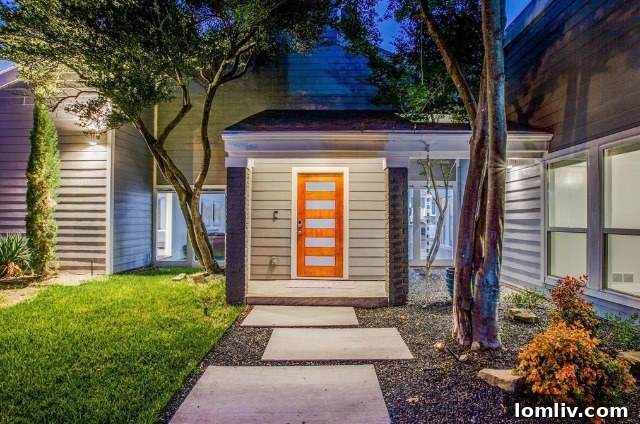 After renovation: Stylish cool gray brick exterior with large windows and an orange accent door at 7015 Duffield Drive