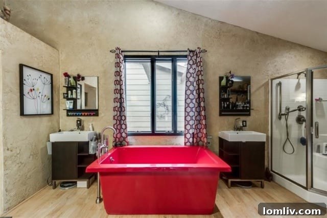 Luxurious primary bathroom featuring a striking red jetted freestanding bathtub