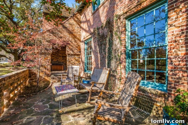The impressive front entrance of the Tudor home, featuring a rustic stone- and wood-beamed porch that overlooks a walled stone patio.