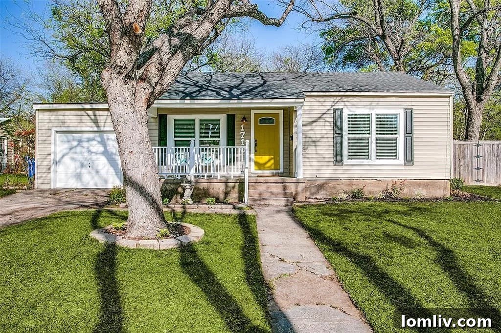Close-up view of the welcoming covered porch with a canary yellow front door and modern light fixture on the renovated Carrollton cottage.