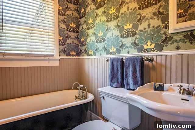 Vintage bathroom featuring a classic pedestal sink, claw-foot tub, and elegant William Morris-style wallpaper