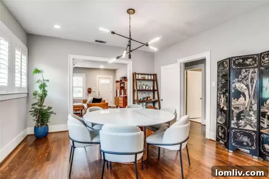 Bright and airy open concept living and dining area, featuring modern lighting, plantation shutters, and seamless flow.