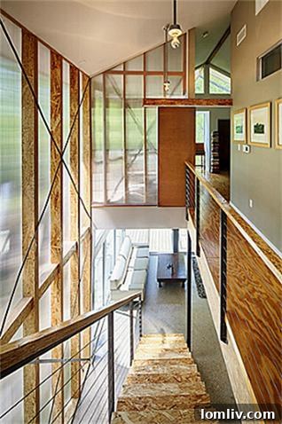 Architectural staircase at 8643 Groveland, bathed in natural light from the two-story polycarbonate wall, connecting levels.