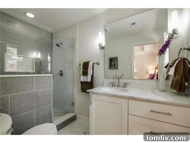 Modern master bathroom with a walk-in shower, half-wall, and marble-topped vanity.