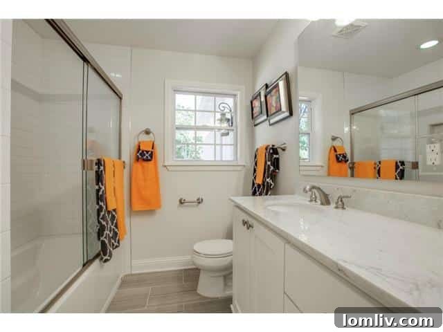 Sleek hall bathroom featuring a marble vanity and plenty of storage.