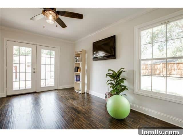 Bright and versatile bonus room staged as a studio, with French doors leading to the deck.