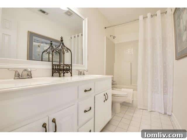 Functional master bathroom featuring dual sinks and a practical tub/shower combination