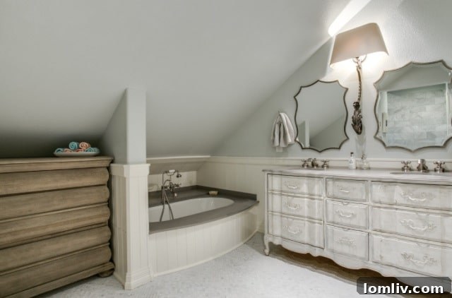 A serene and luxurious upstairs bathroom in Stacey Warnix's renovated Tudor, showcasing modern fixtures elegantly integrated with the home's historic character.