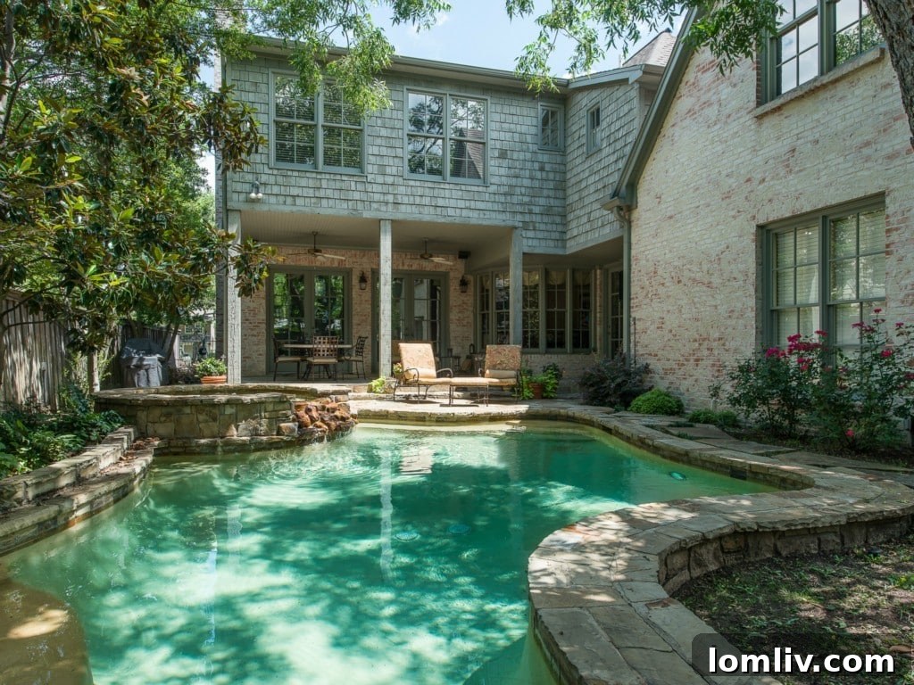 Stunning rock-waterfall pool and round spa in the beautifully landscaped backyard of 3325 Greenbrier, perfect for relaxation and entertaining.