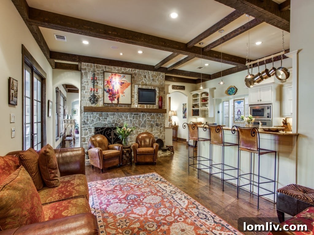 Luxurious living room at 6832 Avalon Ave, Dallas TX, showcasing stunning beamed ceilings and a cleverly integrated TV within a stone fireplace for a seamless design.