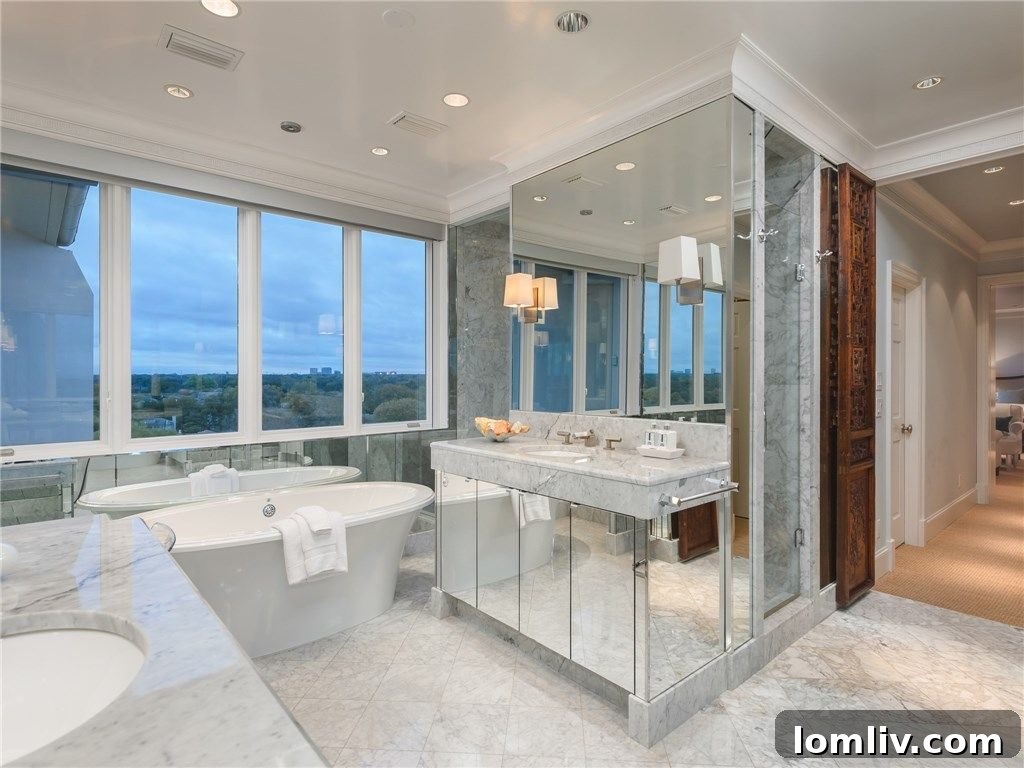 Opulent master bathroom with dual vanities, a freestanding tub, a spacious glass shower, and Carrara marble.