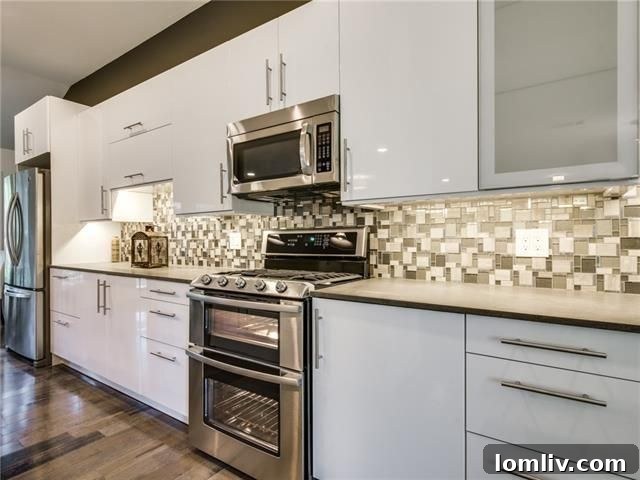 Sleek kitchen featuring white lacquer cabinets, stainless steel appliances, and a stylish glass backsplash.