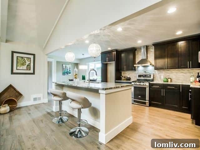 Gourmet kitchen with high-end granite, dark espresso cabinets, designer tile backsplash, and sparkling chandeliers.