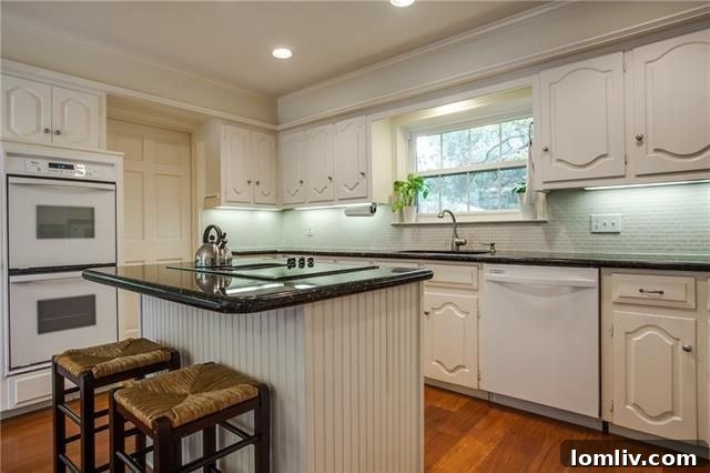 Bright kitchen with white cabinets, granite, and double ovens