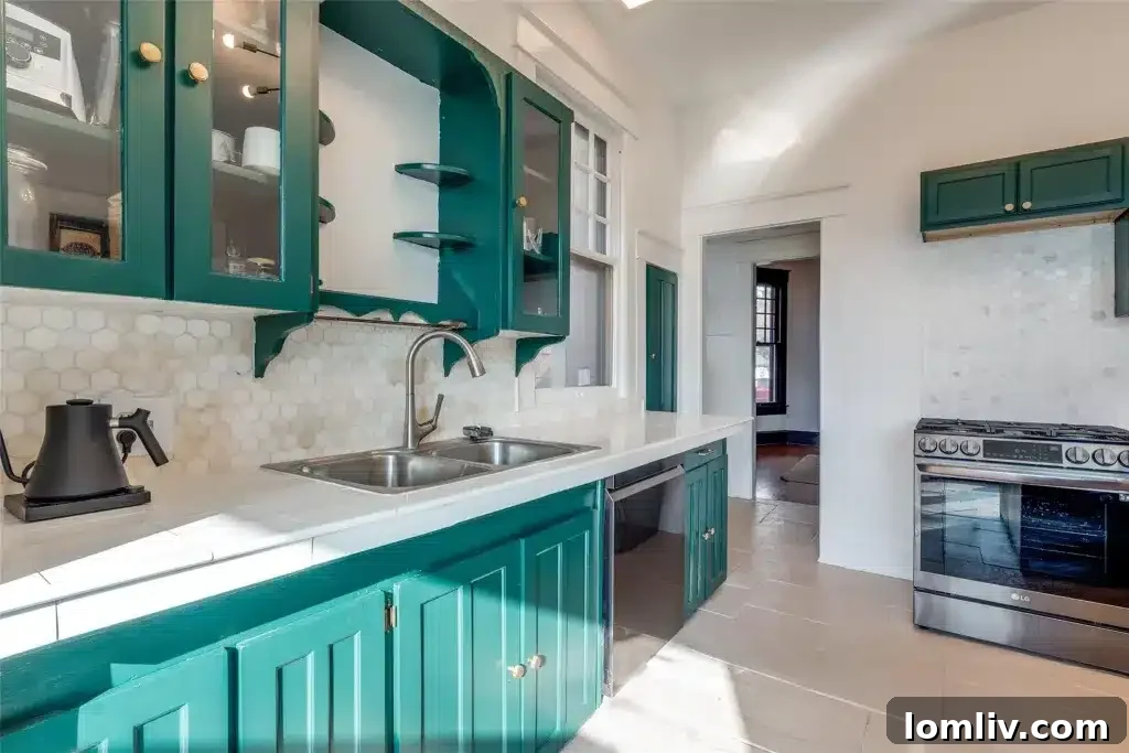A modern kitchen in a historic Winnetka Heights home, featuring rich green cabinetry, a unique honeycomb marble backsplash, and ample counter space.