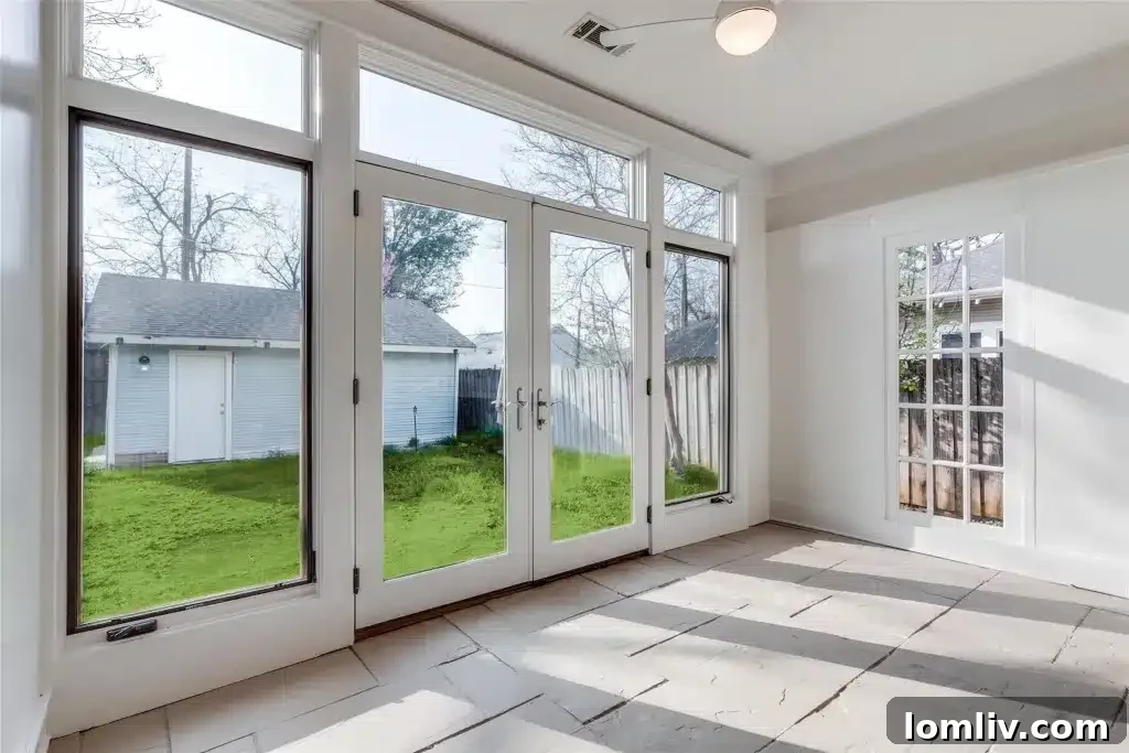 A sun-drenched sunroom in a Winnetka Heights Craftsman, with full-light French doors opening to the backyard, perfect for relaxation.