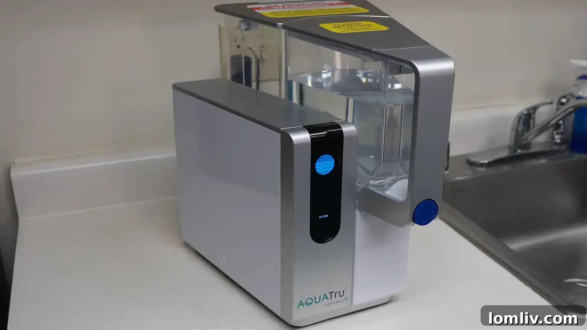 Hand holding a reusable water bottle next to a benchtop water filter, emphasizing environmental sustainability.
