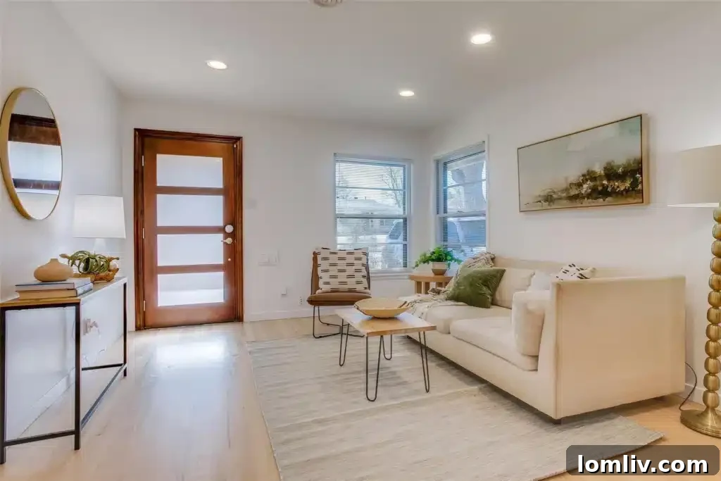 The living room of the Oak Cliff home, showcasing gleaming, restored hardwood floors, ample natural light streaming through large windows, and a fresh, neutral color palette, creating an inviting and spacious atmosphere.