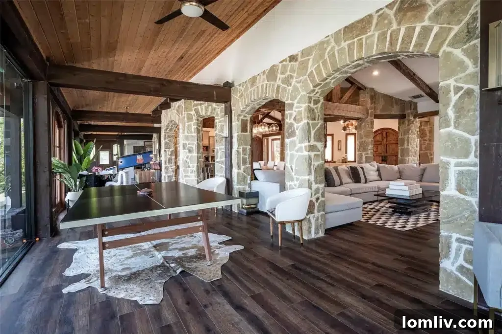 Luxurious primary suite featuring a second elegant stone fireplace, a designer light fixture, and ample space for relaxation.
