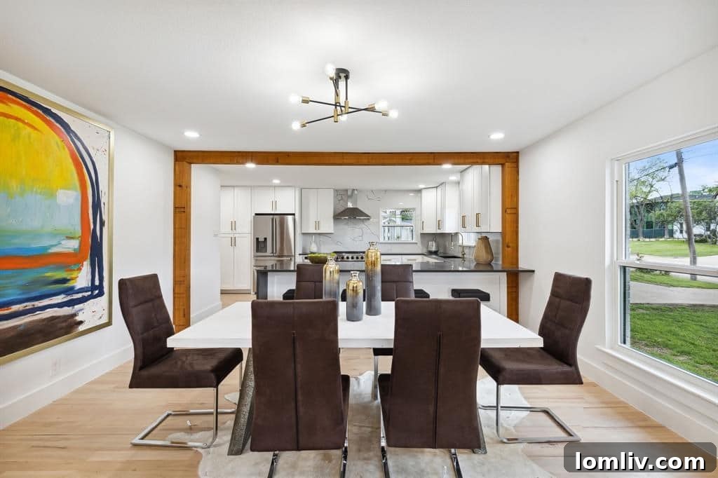 Open concept dining area with sleek chandelier, leading to the kitchen