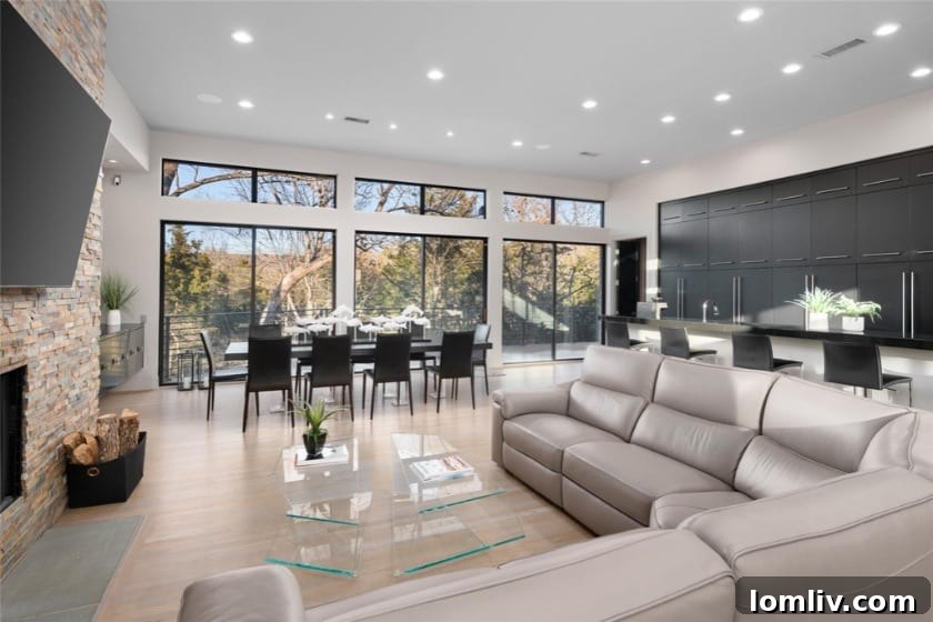 Interior living space of the modern home with large windows, white oak flooring, and a stacked stone fireplace