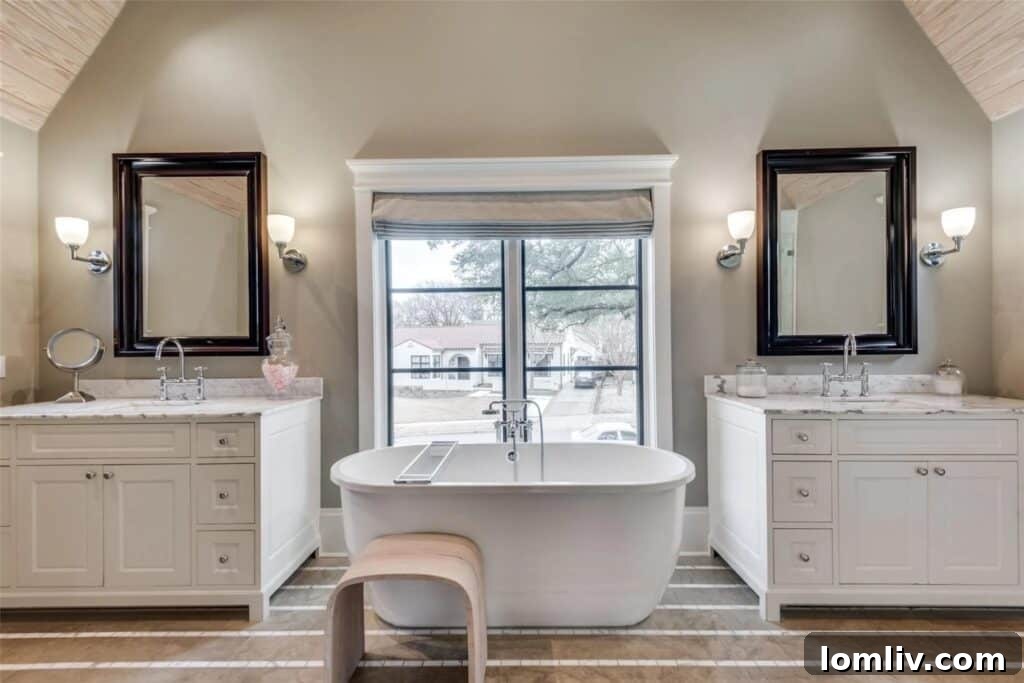 Luxurious primary bathroom featuring a freestanding tub, dual vanities, and contemporary tile work