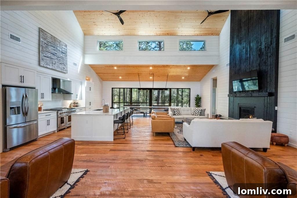 Spacious outdoor deck with a large hot tub, comfortable lounge chairs, and an outdoor dining area, surrounded by lush trees at a Broken Bow luxury rental