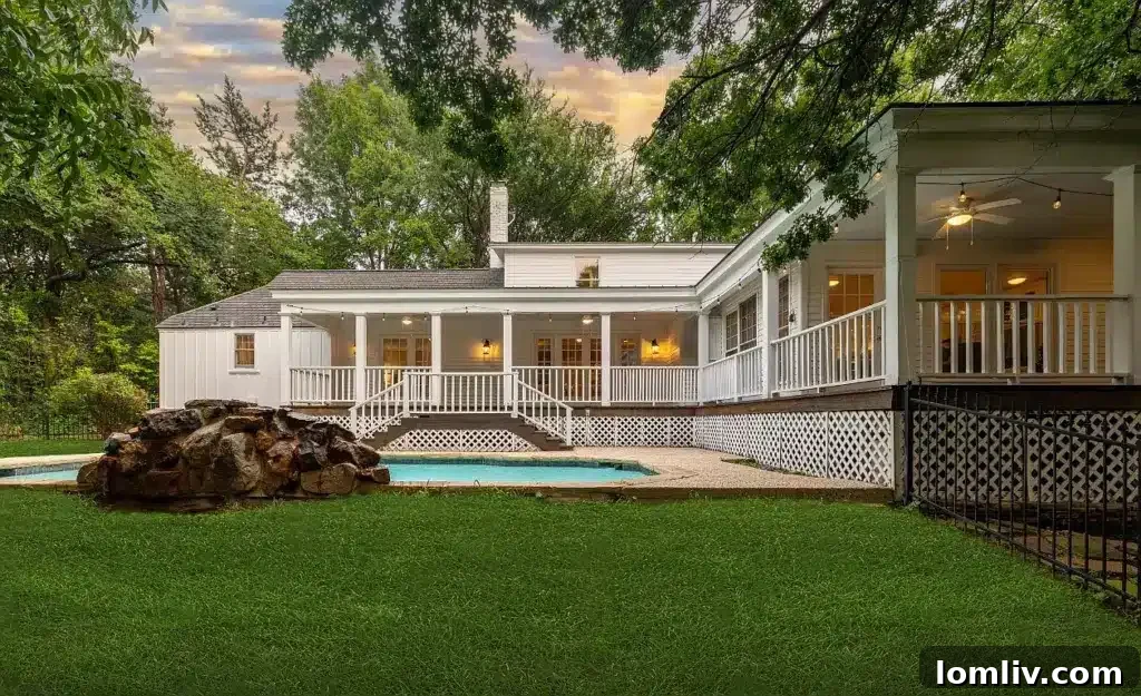 Luxurious backyard with a waterfall pool, wrap-around porch, and pristine landscaping.