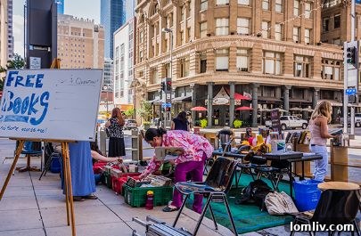 People enjoying a repurposed parking space during Park(ing) Day Dallas 2016, featuring urban greenery and seating.