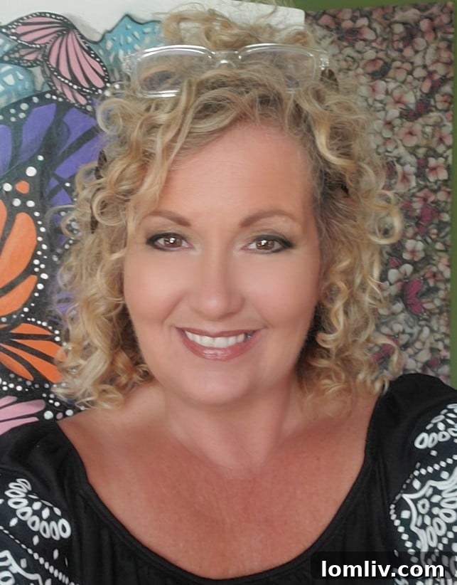 Artist Juju, known as the 'Butterfly Girl,' smiling warmly in a creative setting, surrounded by artistic elements.