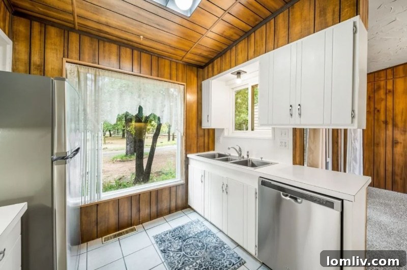The compact, uniquely designed kitchen of the Oklahoma City house, featuring a mix of white-painted and wood-paneled cabinetry.