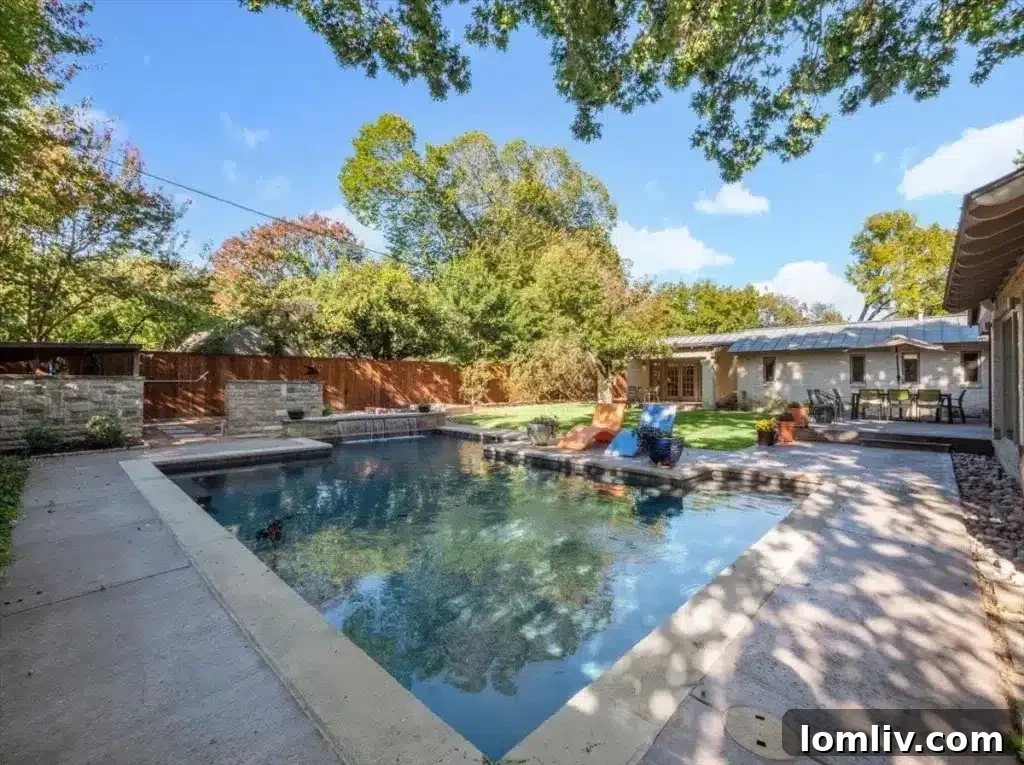 Spacious backyard with a rolling green lawn, mature trees, and direct access to the inviting pool area, perfect for family fun.