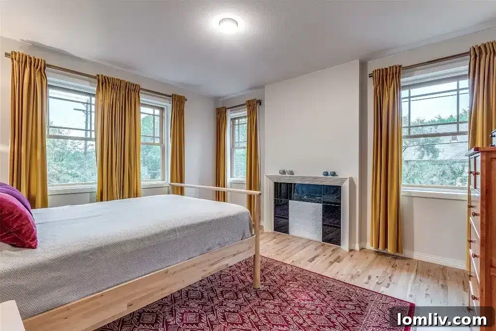 Primary bedroom with large windows, faux hearth, and serene ambiance