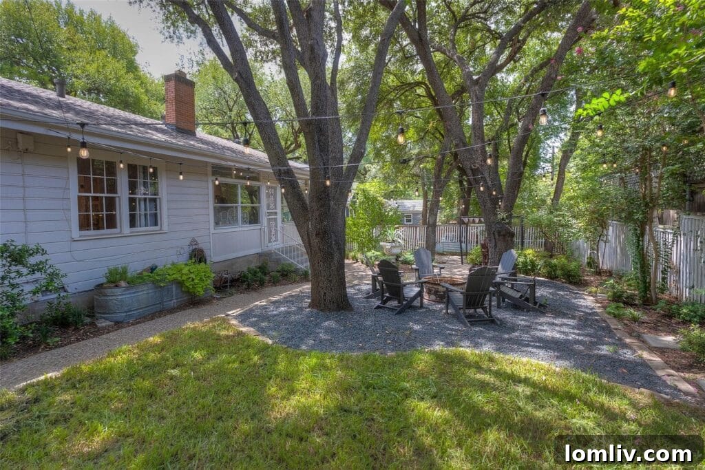 Outdoor fire pit area with string lights, nestled between two live oaks in the landscaped yard of the Oakhurst bungalow.