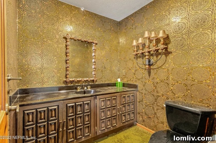 Bathroom with green shag carpet and striking, reflective vintage wallpaper, showcasing unique Midcentury design