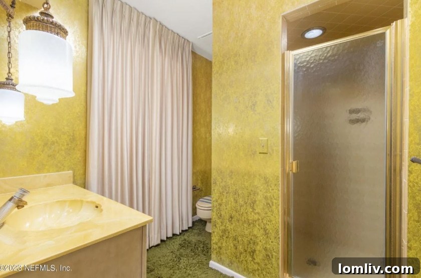 Another view of a Midcentury Modern bathroom with green shag, shiny wallpaper, and retro fixtures