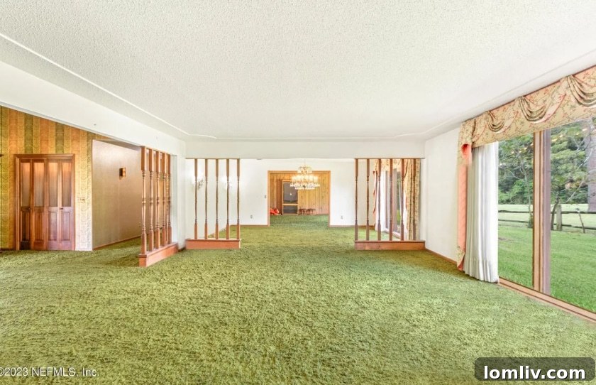 Formal living room of a Midcentury Modern home with green shag carpet, large windows, and vintage decor