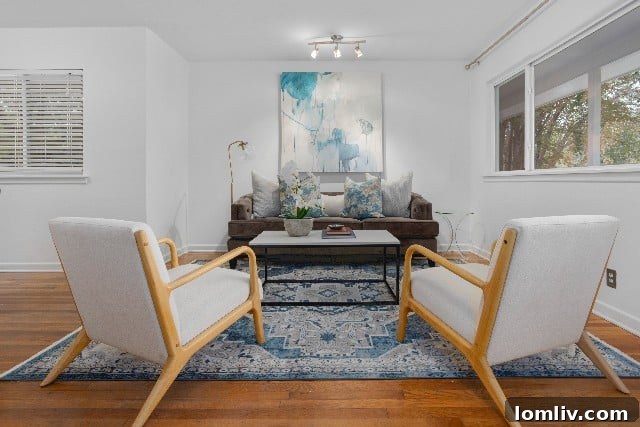 Spacious living area featuring original hardwood floors and large windows, creating a bright and inviting atmosphere