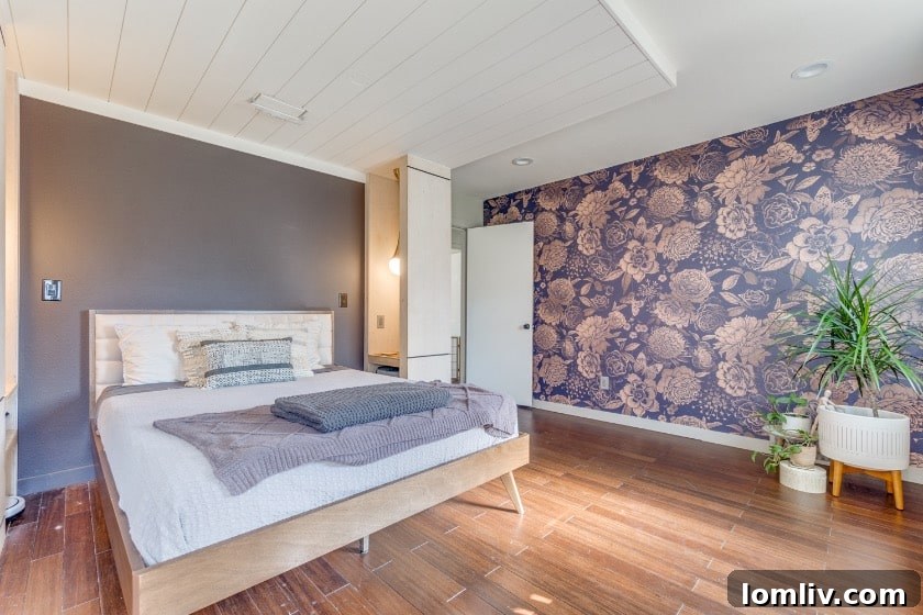 The newly designed primary bedroom with dark, textured wallpaper, custom built-in nightstands, and a cozy ambiance.