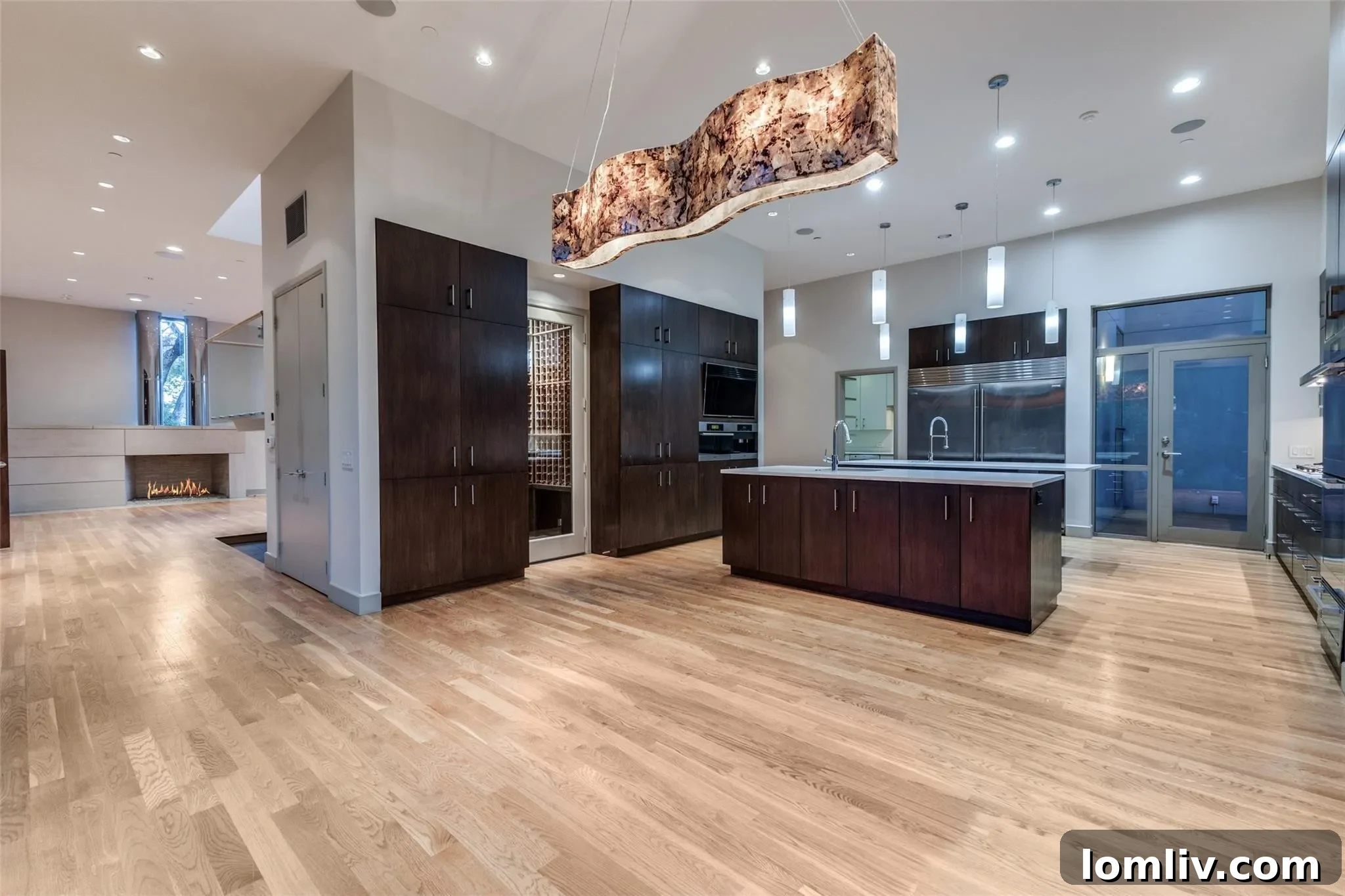 Gourmet kitchen with large island, high-end stainless steel appliances, and a visible glass-enclosed wine room