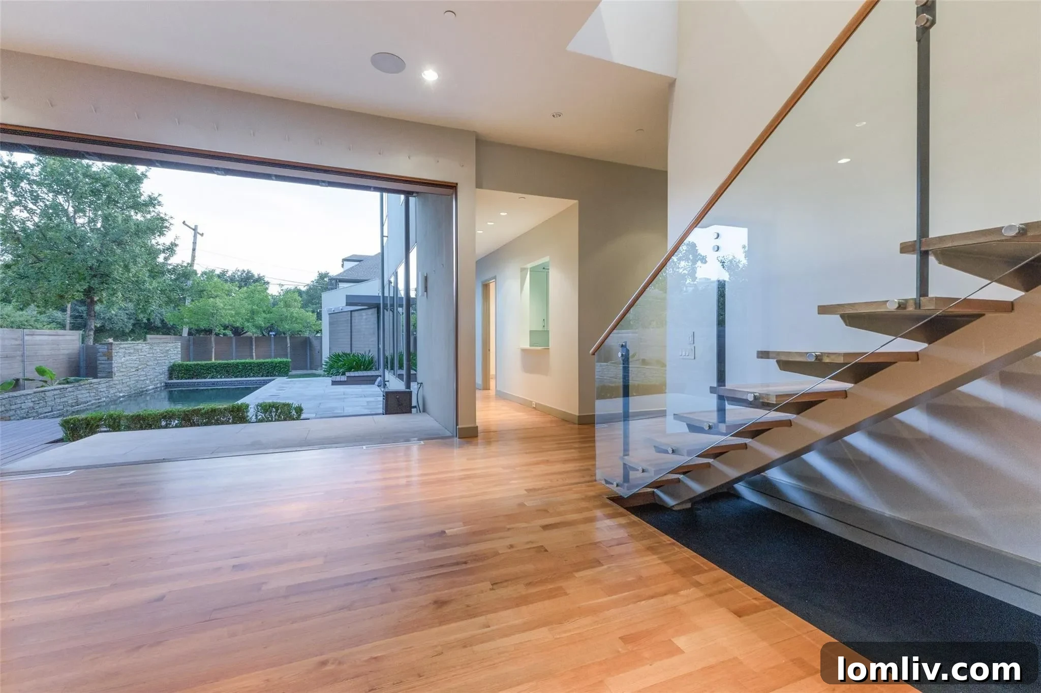Living room with contemporary furniture opening directly to a private swimming pool and a well-manicured outdoor patio