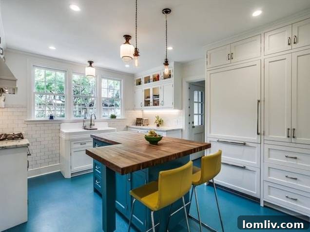 Luxurious kitchen island with bold teal cabinetry, Danby white marble, and walnut butcher block