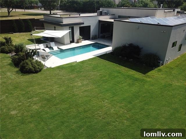 Sophisticated backyard with green space, modern pool, and shade sail for relaxation