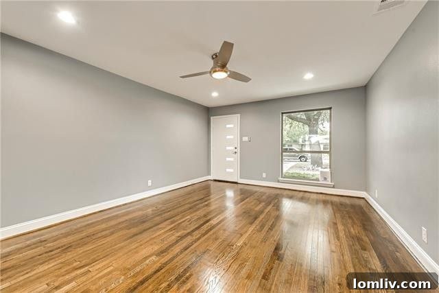 Bright, open concept living area after extensive renovation, featuring hardwood floors