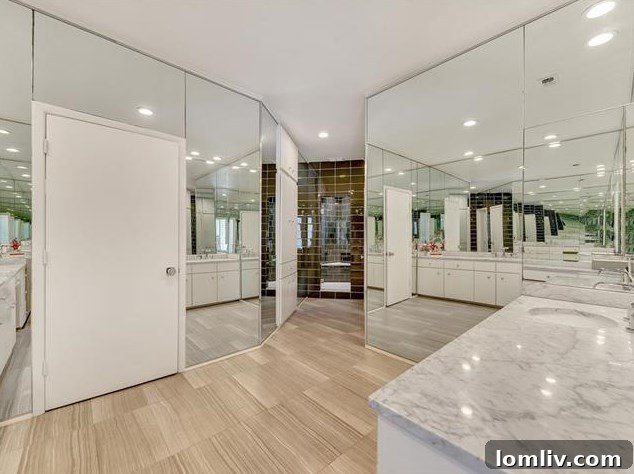 Luxurious master bathroom with mirrored walls, glass tile, and Carrara marble vanity