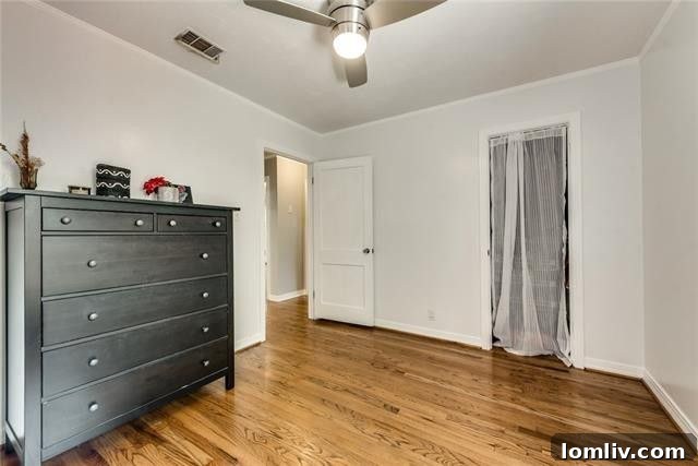 Bright master bedroom with ample space, pristine hardwood floors, and large windows inviting natural light